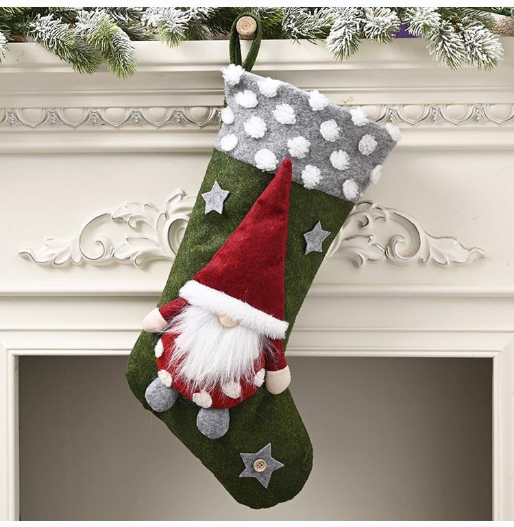 Green Christmas stocking with white polka dot cuff and gnome decoration hanging on mantle with snowy garland