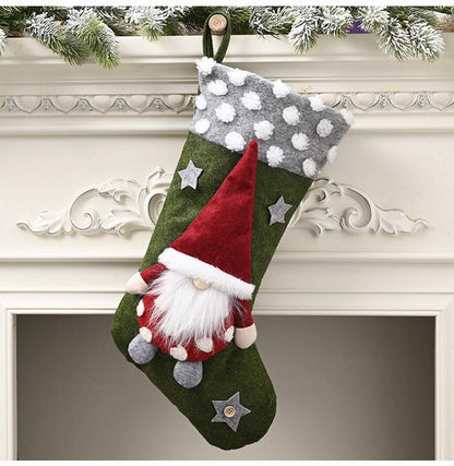 Green Christmas stocking with white polka dot cuff and gnome decoration hanging on mantle with snowy garland