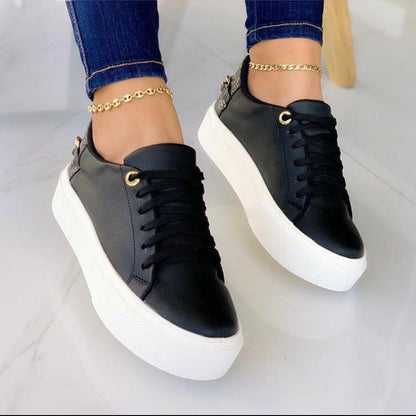 black leather platform sneakers with white soles worn with blue jeans and gold anklets on tiled floor