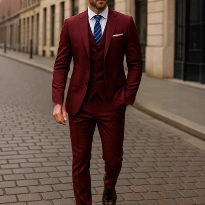 Man wearing a tailored burgundy three-piece suit with blue striped tie walking on a cobblestone street