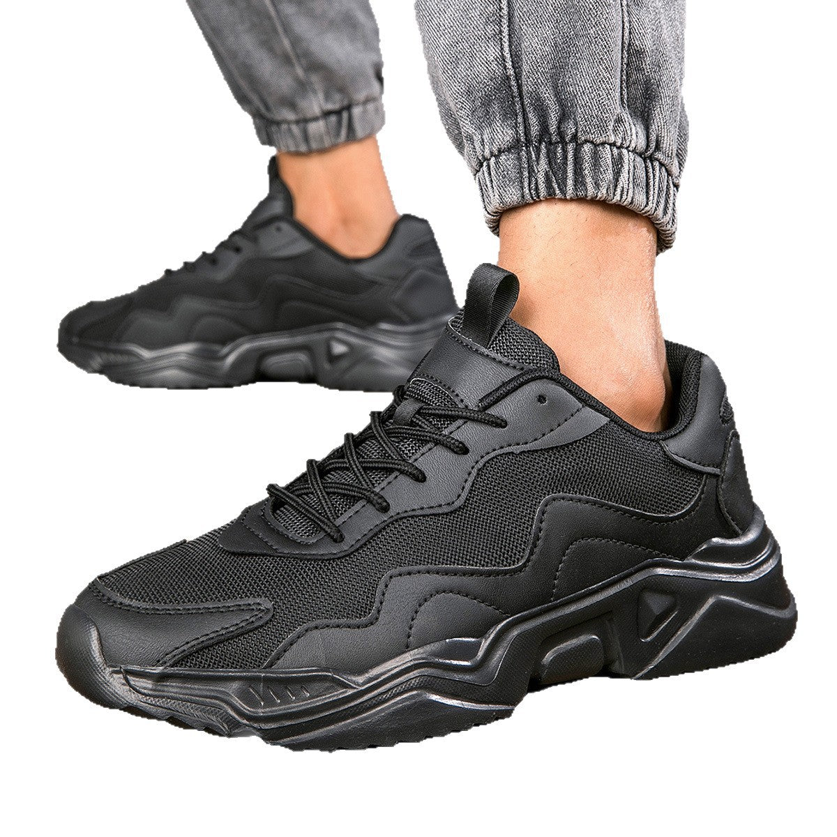 Black chunky sneakers with textured mesh and synthetic overlays worn with rolled gray jogger pants