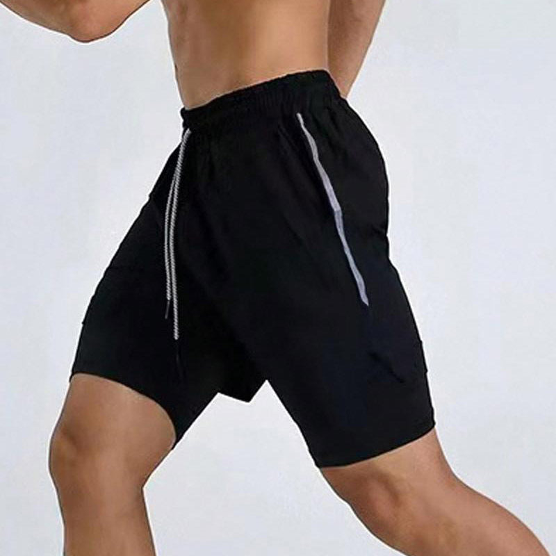 Athletic man wearing black running shorts with reflective stripes and drawstring against white background