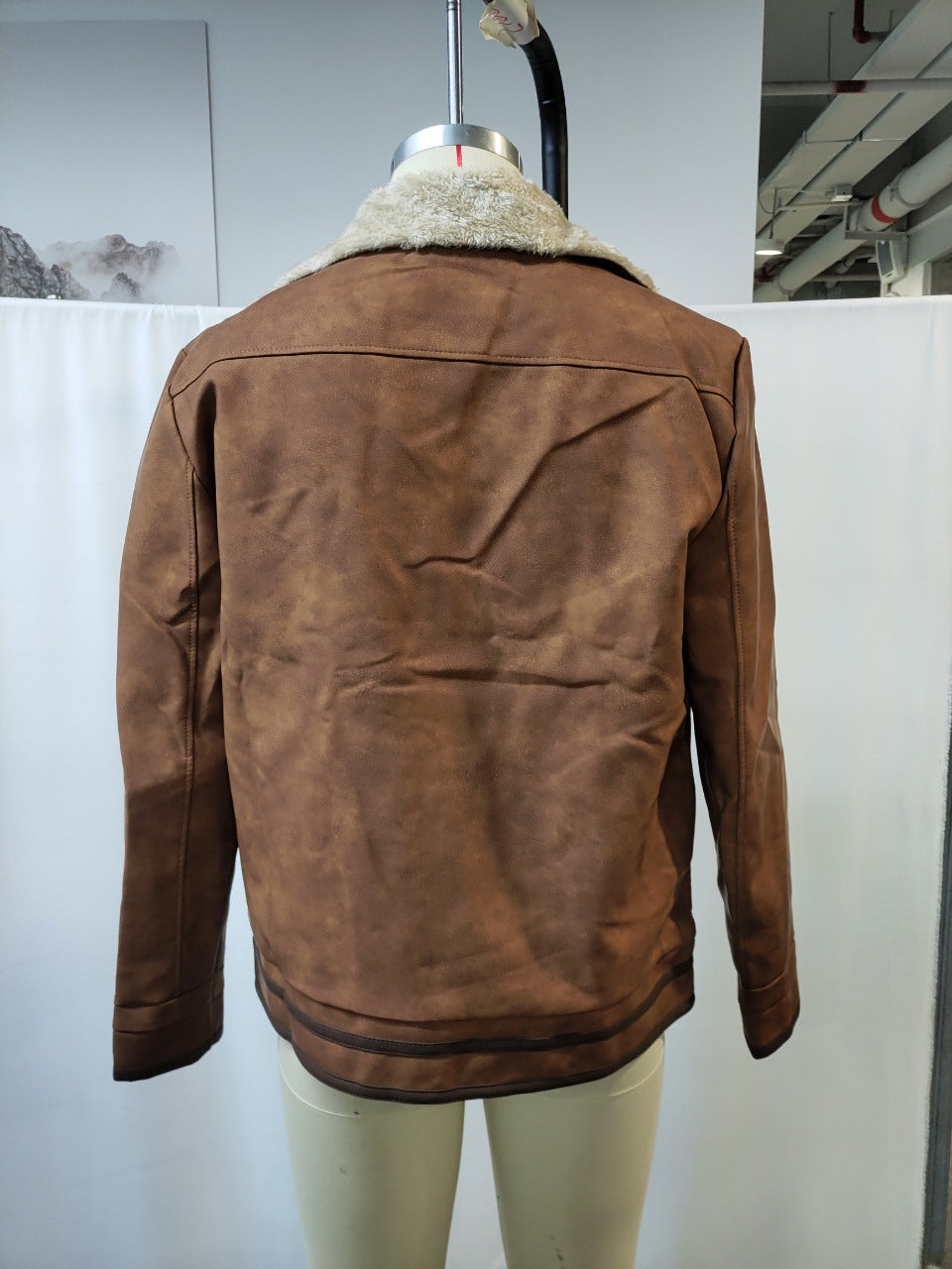 Back view of brown suede jacket with cream shearling collar on mannequin in indoor setting