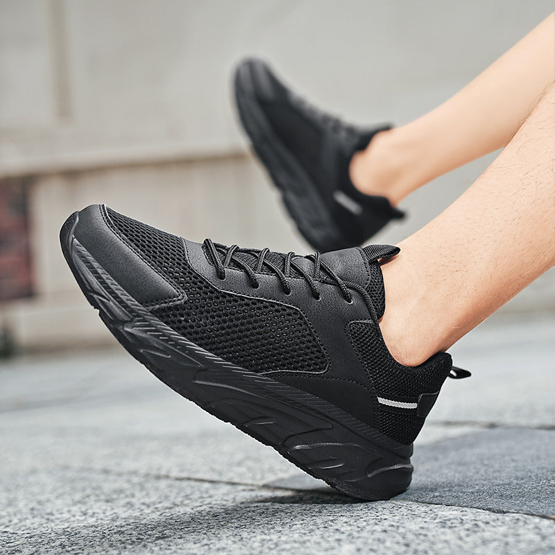Close-up of black breathable mesh sneakers with thick sole worn outdoors on pavement