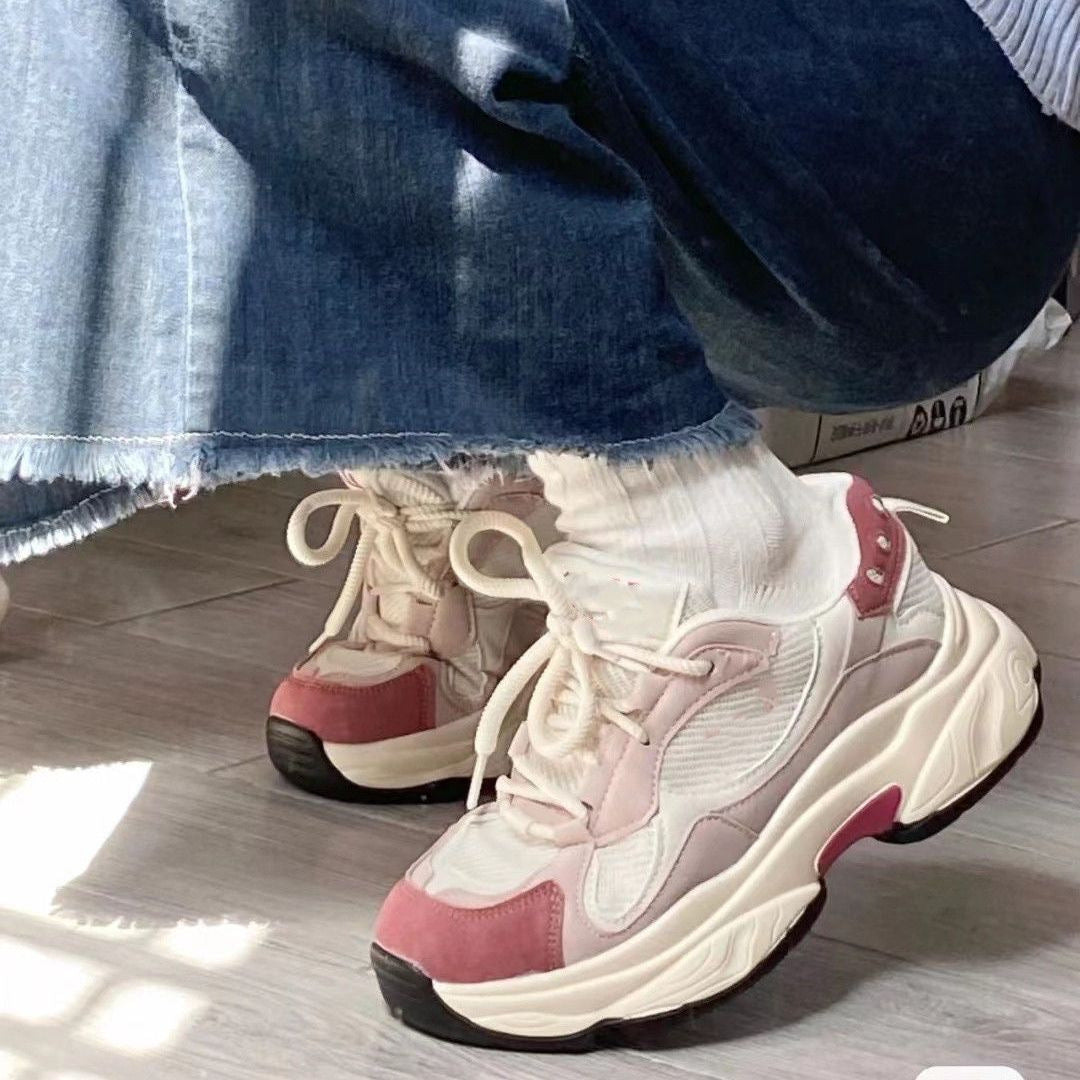 Chunky white and pink sneakers with beige laces worn with white socks and frayed hem denim jeans