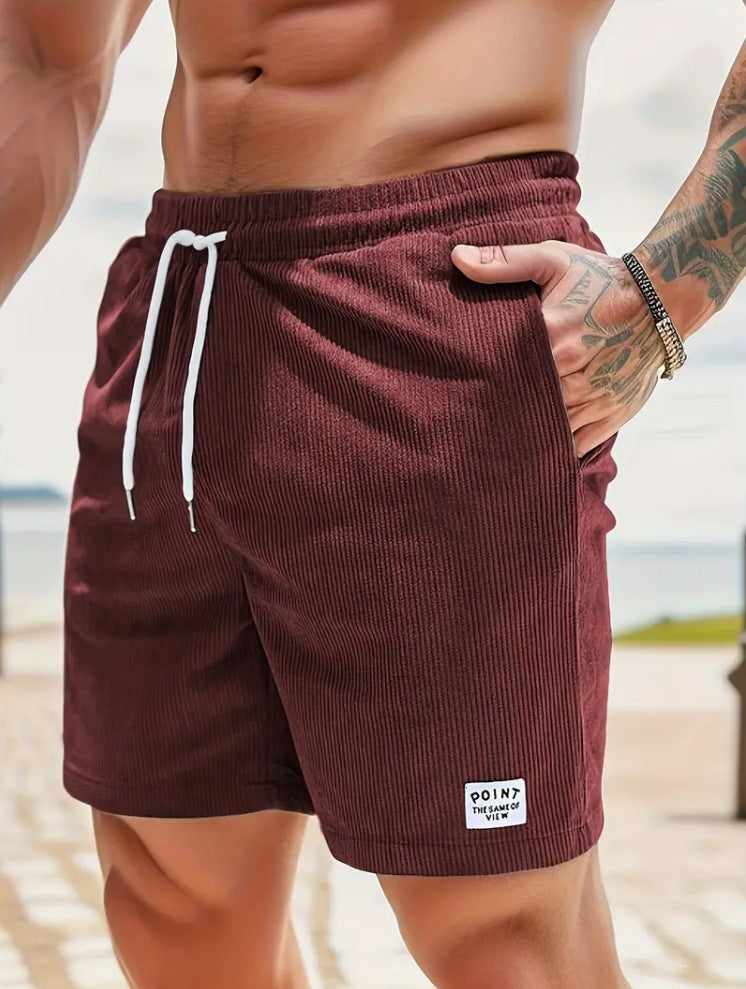 Close-up of a man wearing maroon ribbed shorts with white drawstring and a tattooed arm
