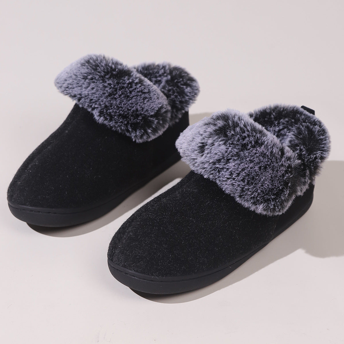 Black cozy indoor slippers with plush gray faux fur lining and trim on a light background