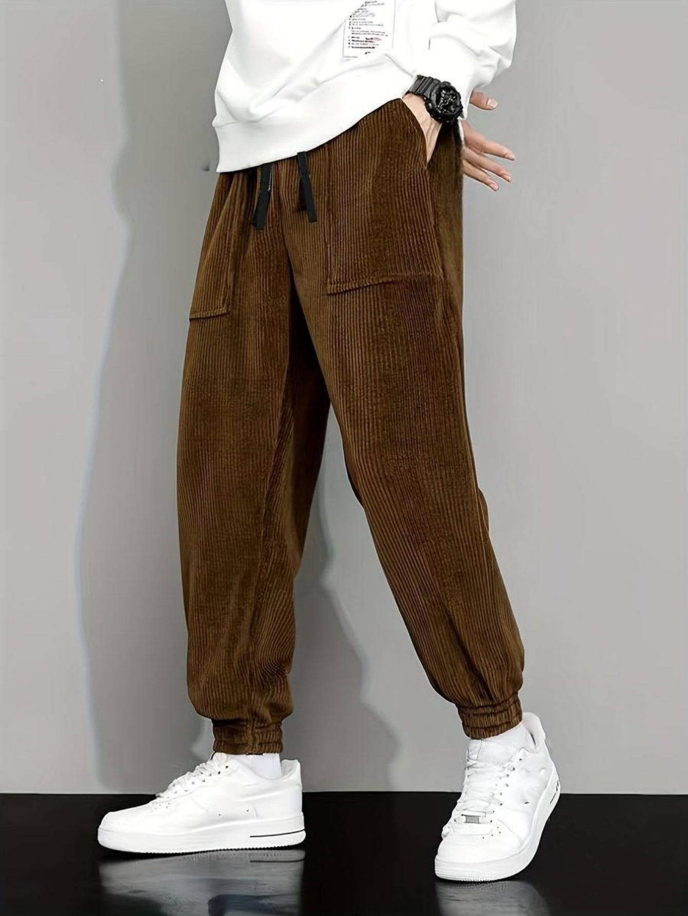 Brown corduroy jogger pants with elastic cuffs paired with white sneakers and a white sweatshirt