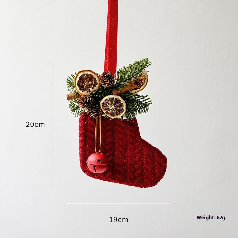 Red knitted Christmas stocking ornament with pine cones, dried orange slices, cinnamon sticks, hanging on red ribbon