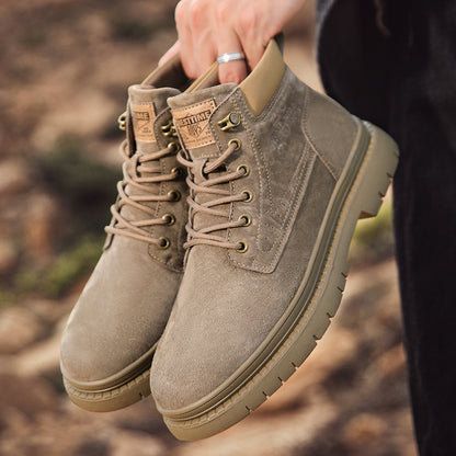 Hand holding beige suede lace-up boots with rugged soles outdoors