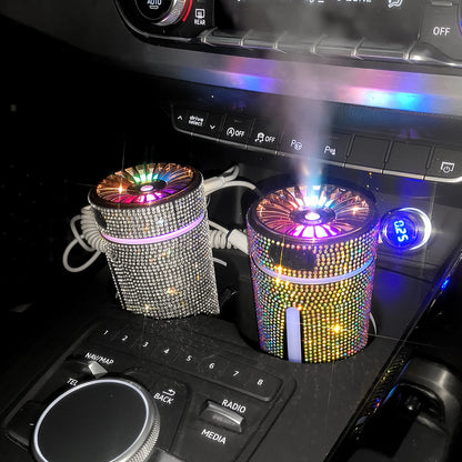Car interior with two rhinestone-covered LED air humidifiers in cup holders emitting colorful light and mist