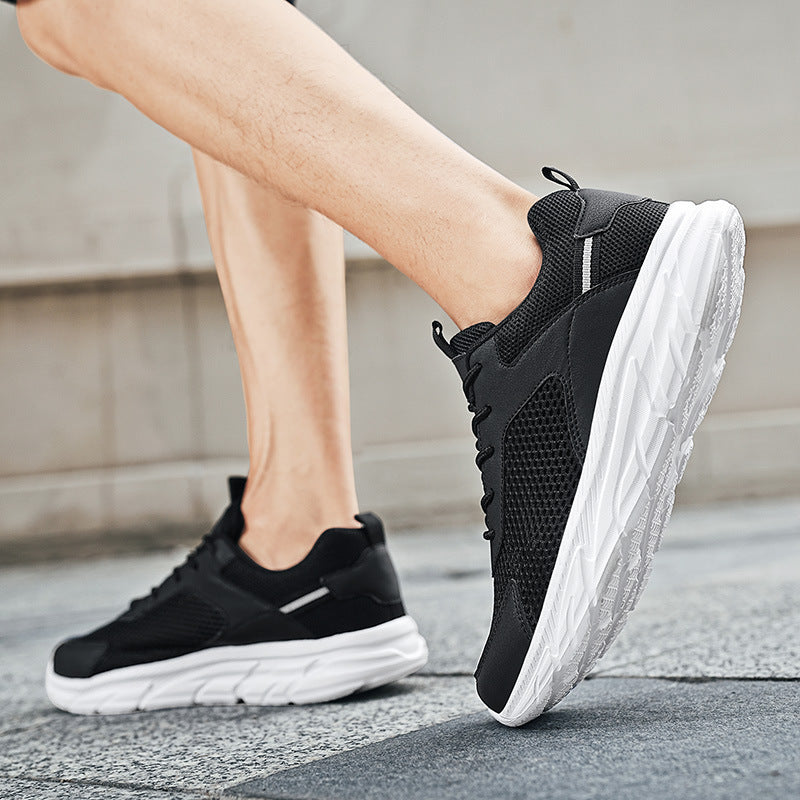 Close-up of black mesh athletic sneakers with thick white soles worn on pavement