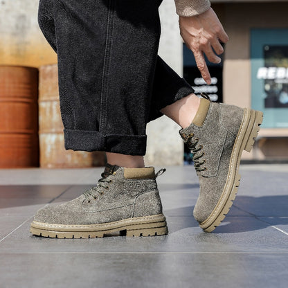 Close-up of grey suede ankle boots with beige soles on tiled floor, black cuffed pants visible