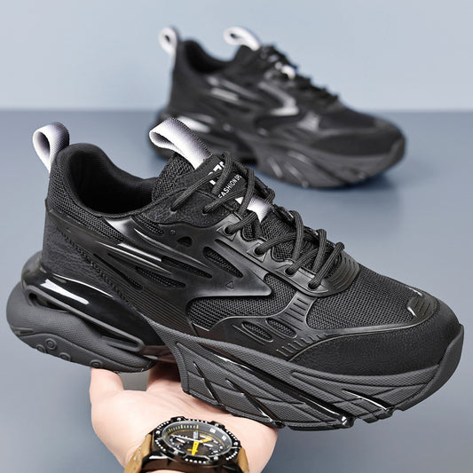 Black chunky sneaker with mesh and synthetic overlays, held in hand, styled for fashion and sport