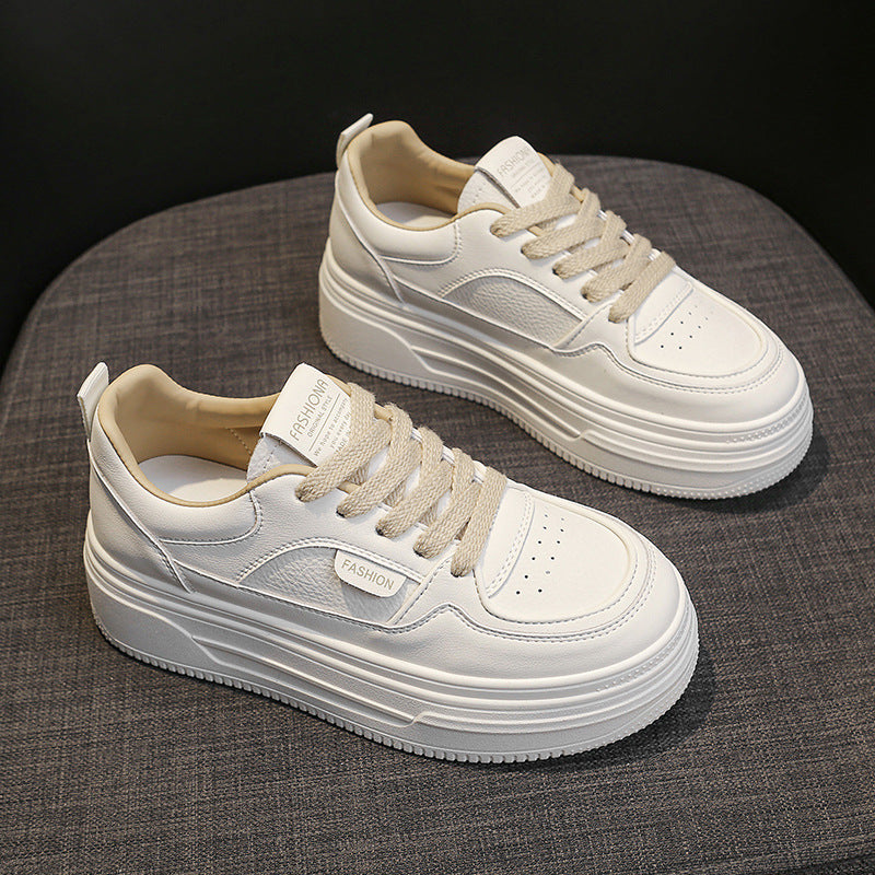 Pair of stylish white platform sneakers with beige laces on gray fabric surface