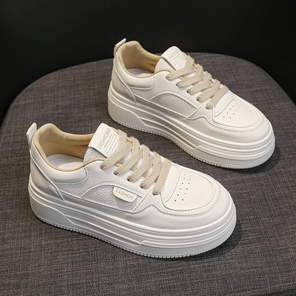 Pair of stylish white platform sneakers with beige laces on gray fabric surface