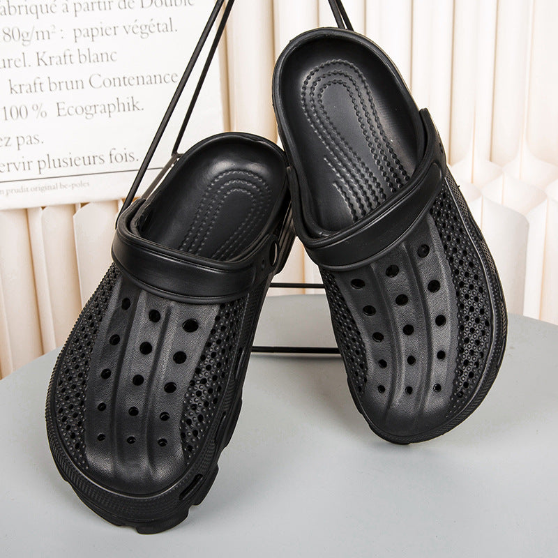 Pair of black perforated slip-on clogs with adjustable strap displayed on gray surface
