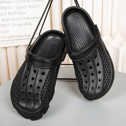 Pair of black perforated slip-on clogs with adjustable strap displayed on gray surface