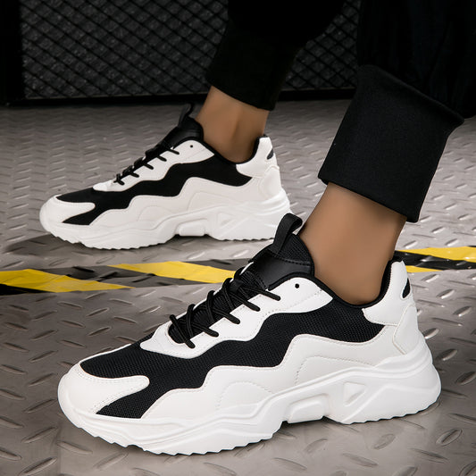 Black and white chunky sneakers on model standing on metallic floor with yellow tape
