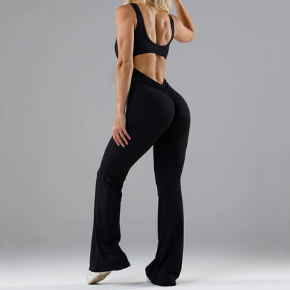Fit woman wearing black scrunch butt leggings and sports bra, posing against gray background