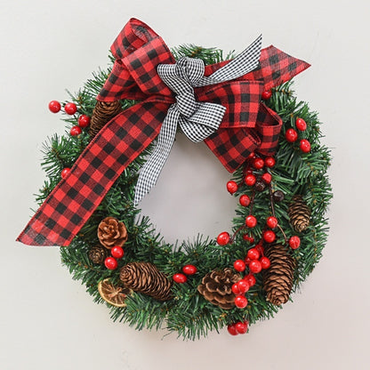 Christmas wreath with green pine branches, red berries, pine cones, and red and black plaid bows