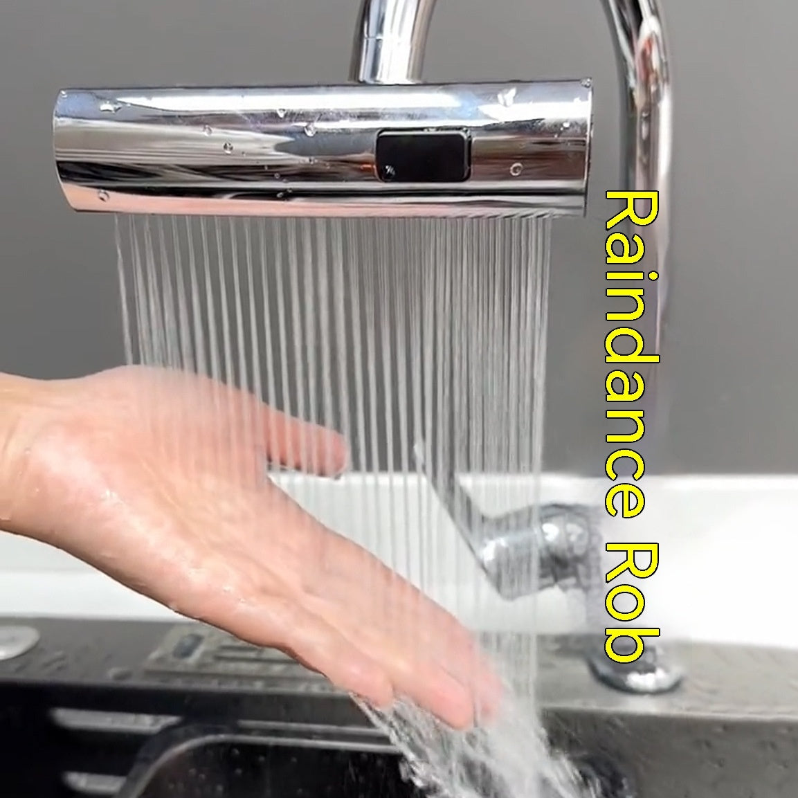 Hand under modern chrome electronic faucet with water streams in kitchen sink
