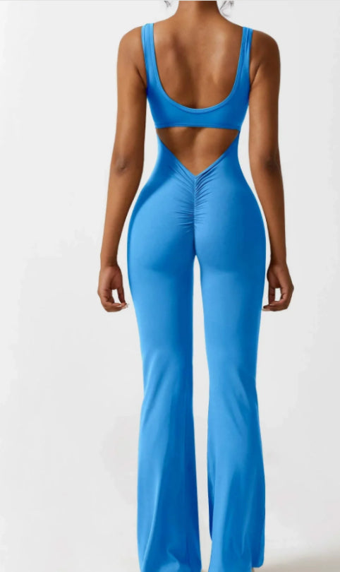 Back view of woman wearing blue cutout fitted jumpsuit with flared legs and ruched detailing