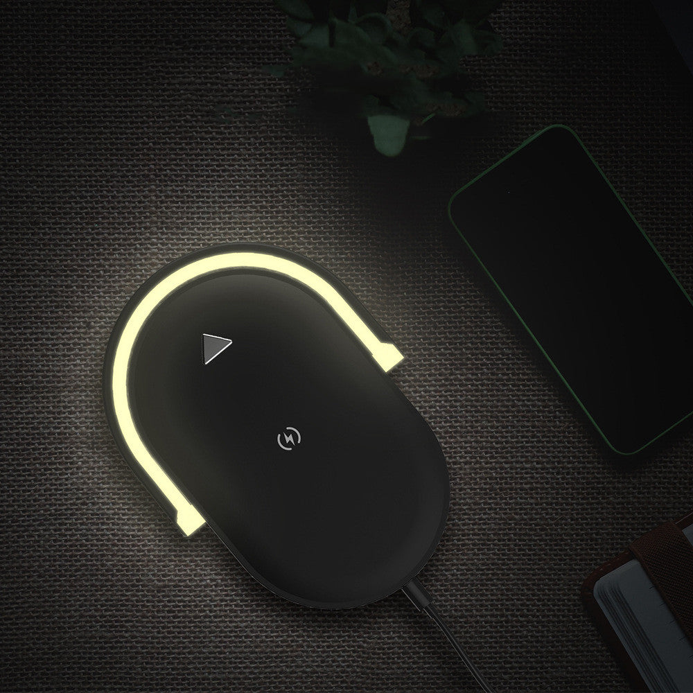 Wireless charging pad with glowing LED light on textured surface near smartphone and notebook