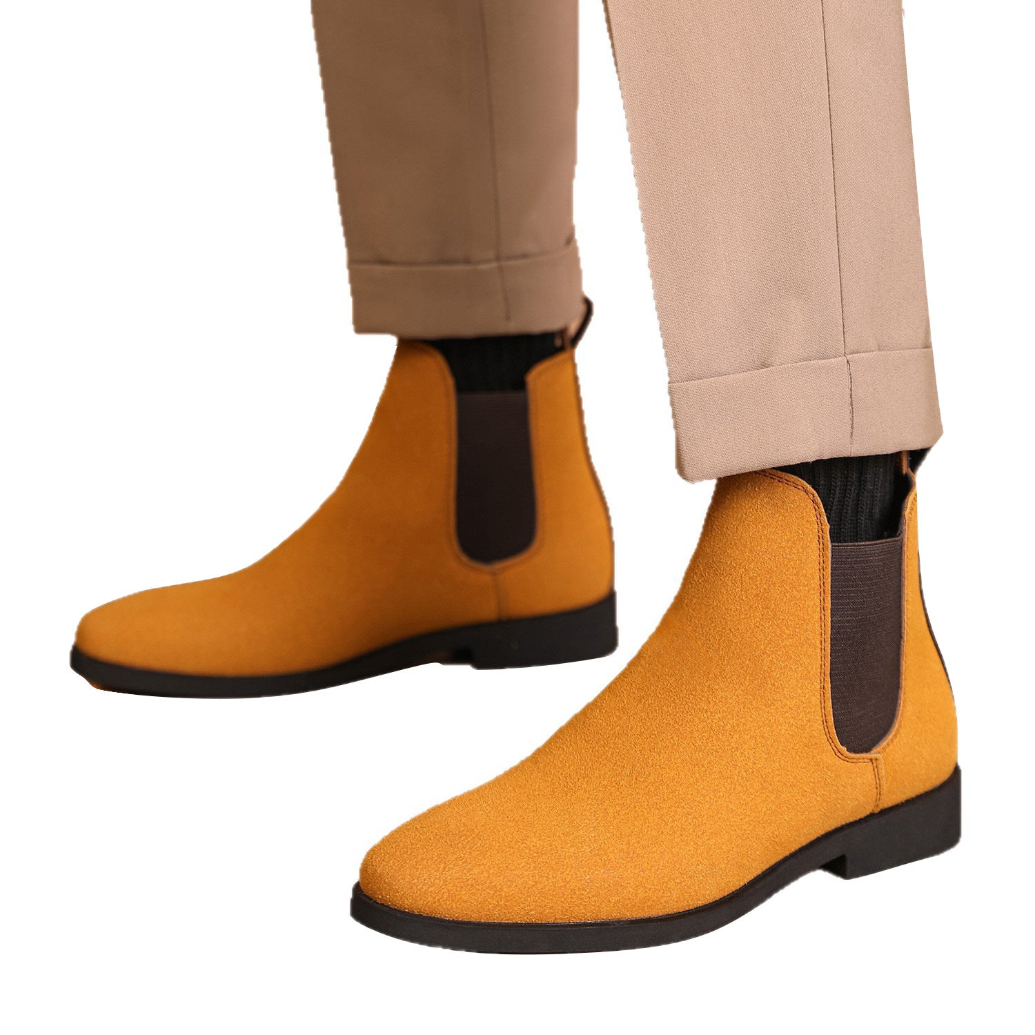 Pair of stylish mustard suede Chelsea boots with black elastic sides worn with beige pants