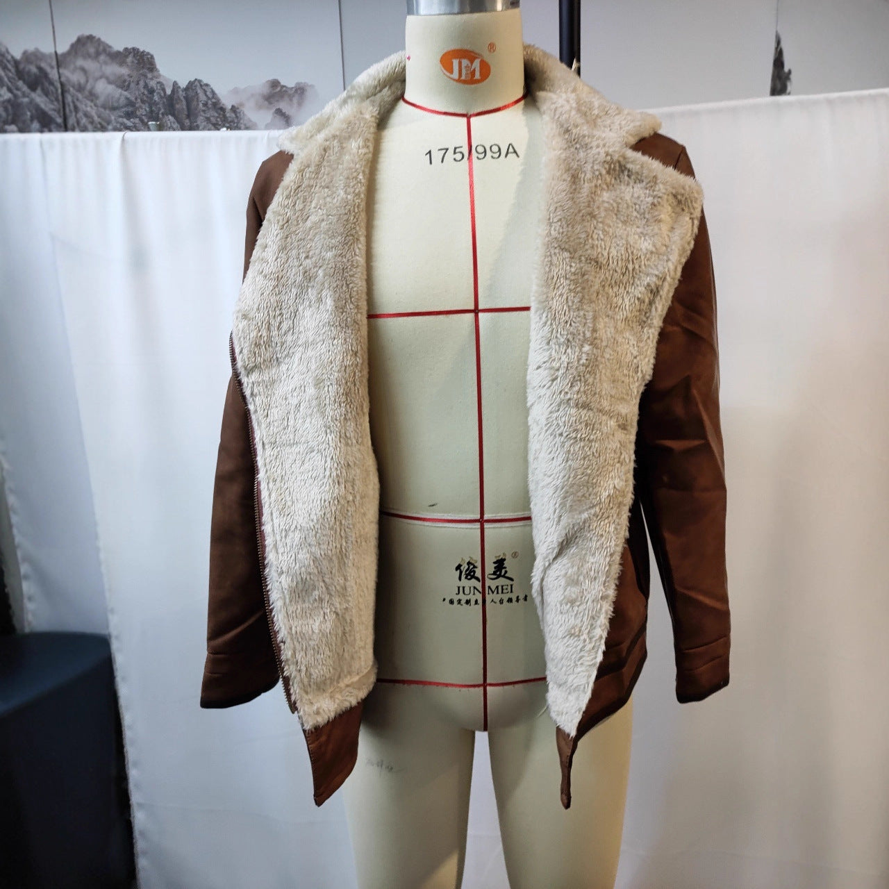 Brown suede jacket with beige faux fur lining displayed on a sewing mannequin in indoor setting