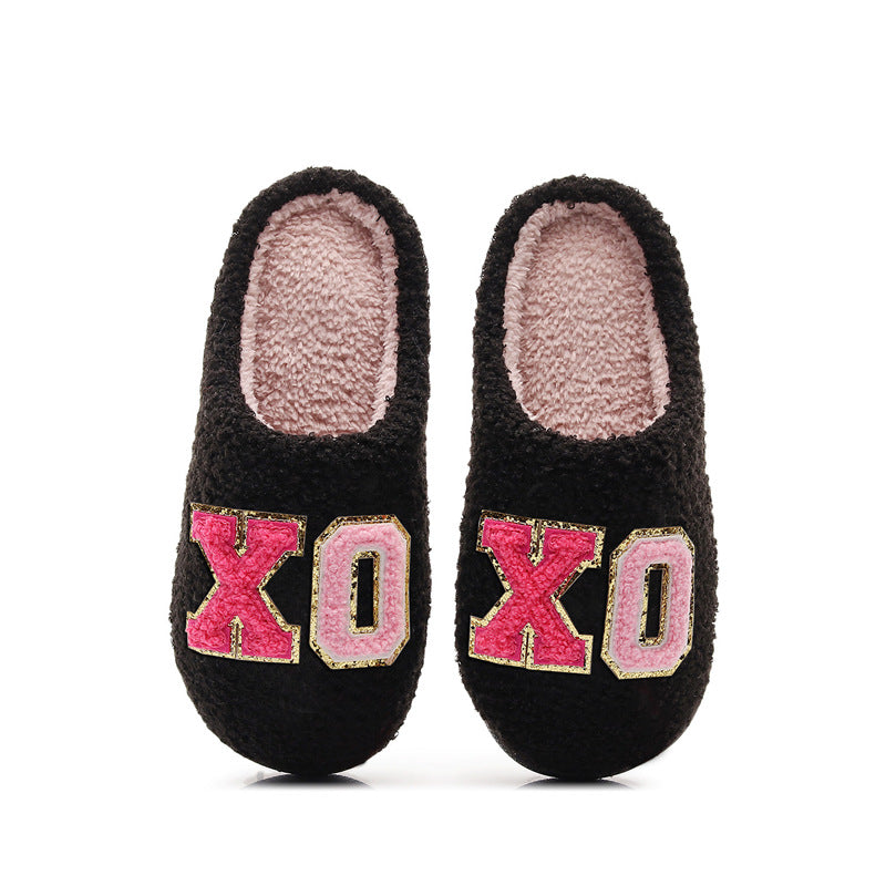 Black cozy slippers with pink soft lining and XO patches in red and pink on top