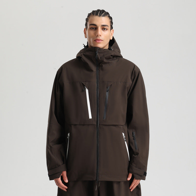 Young man wearing a dark brown zip-up hooded jacket with multiple zippered pockets on a gray background