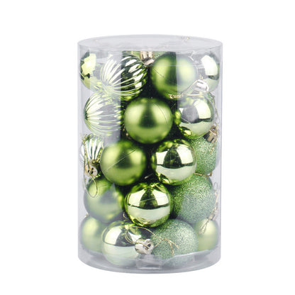 Clear plastic cylinder container filled with assorted green Christmas ornaments in matte, shiny, ribbed, and glitter finishes
