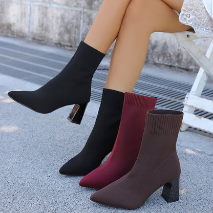 Woman wearing black knit sock boots with pointed toes and block heels, alongside burgundy and brown boots