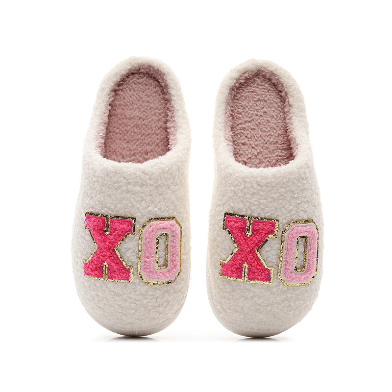 Cozy white sherpa slippers with pink fuzzy 'XO' letters and gold trim, soft indoor footwear