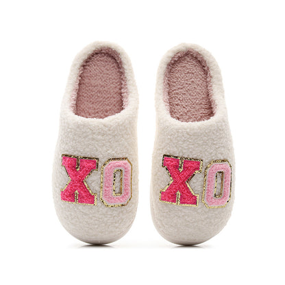 Cozy white sherpa slippers with pink fuzzy 'XO' letters and gold trim, soft indoor footwear