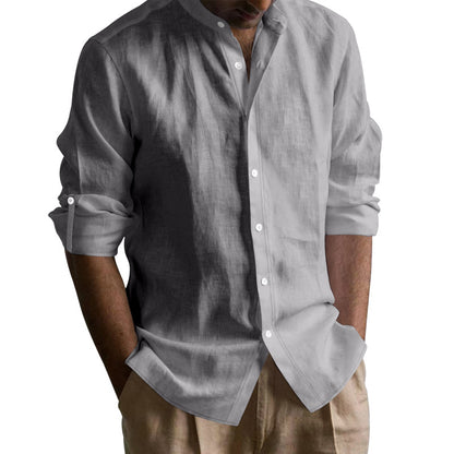 Man wearing a light gray linen shirt with rolled-up sleeves and beige pants against white background