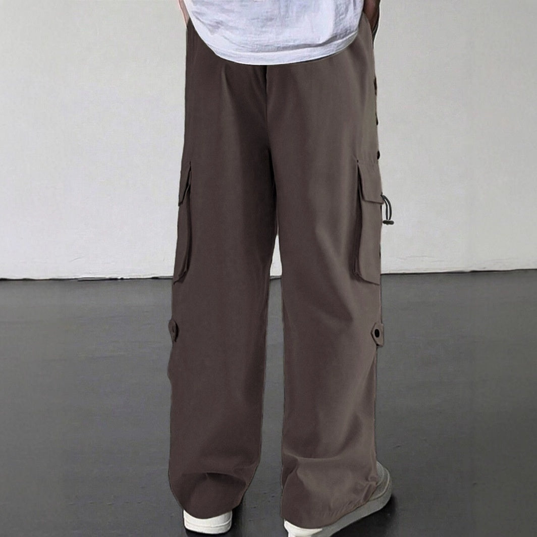 Person wearing loose brown cargo pants with side pockets and white sneakers on gray floor