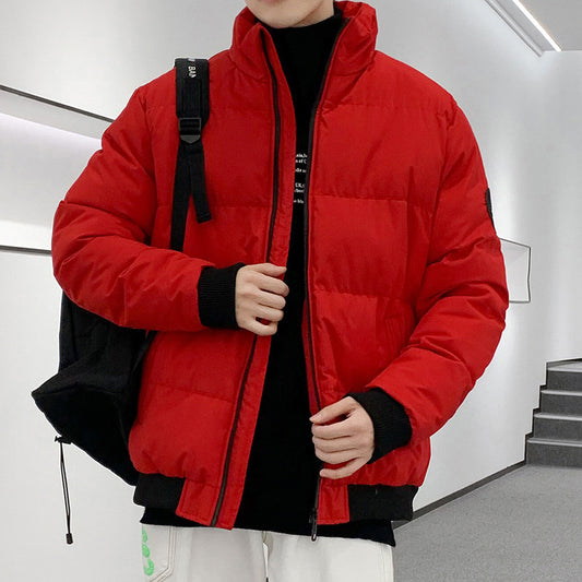 Person wearing bright red quilted puffer jacket with black cuffs, black backpack, and white pants indoors