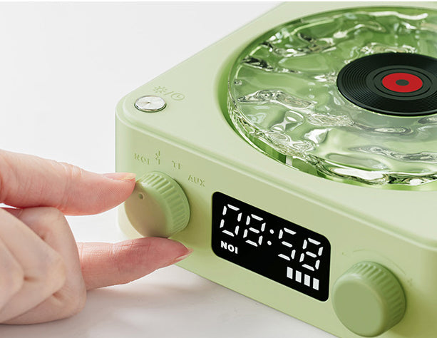 Hand adjusting volume knob on pale green retro-style clock radio with digital display and ice-textured speaker