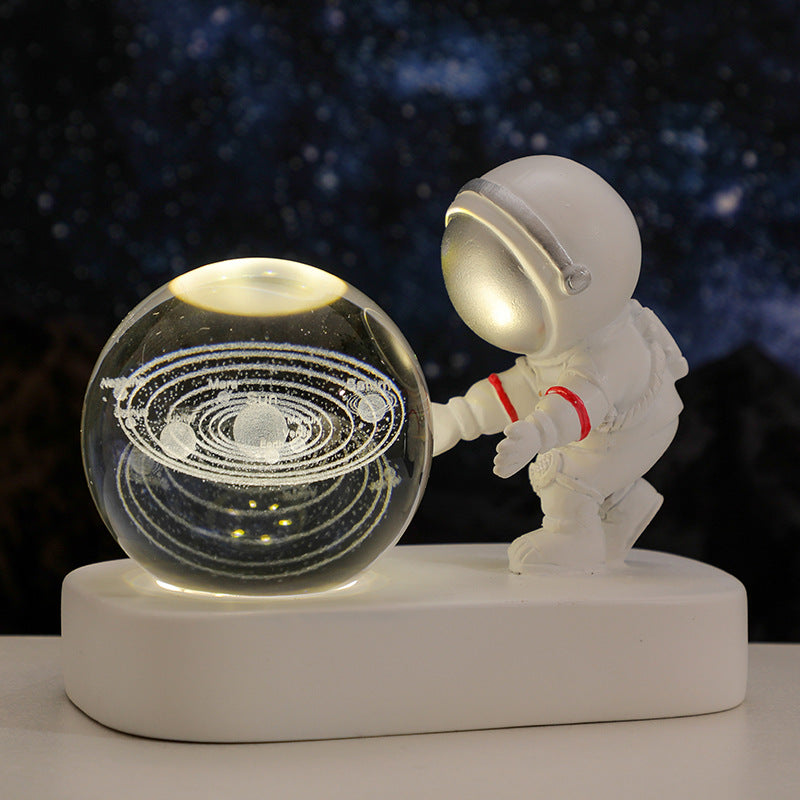 White astronaut figurine with red stripes reaching a crystal ball featuring a glowing solar system model