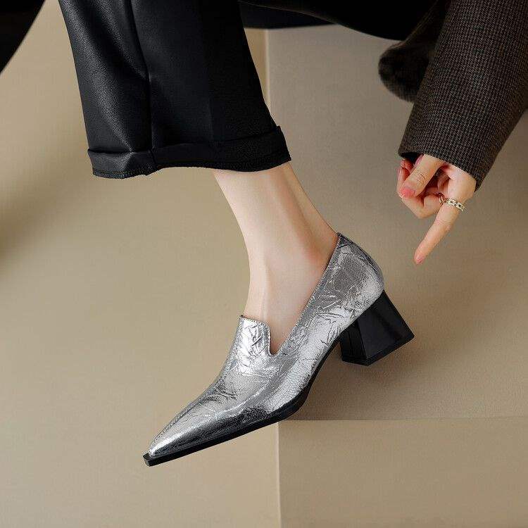 Silver textured leather block heel shoe worn with black pants on beige background