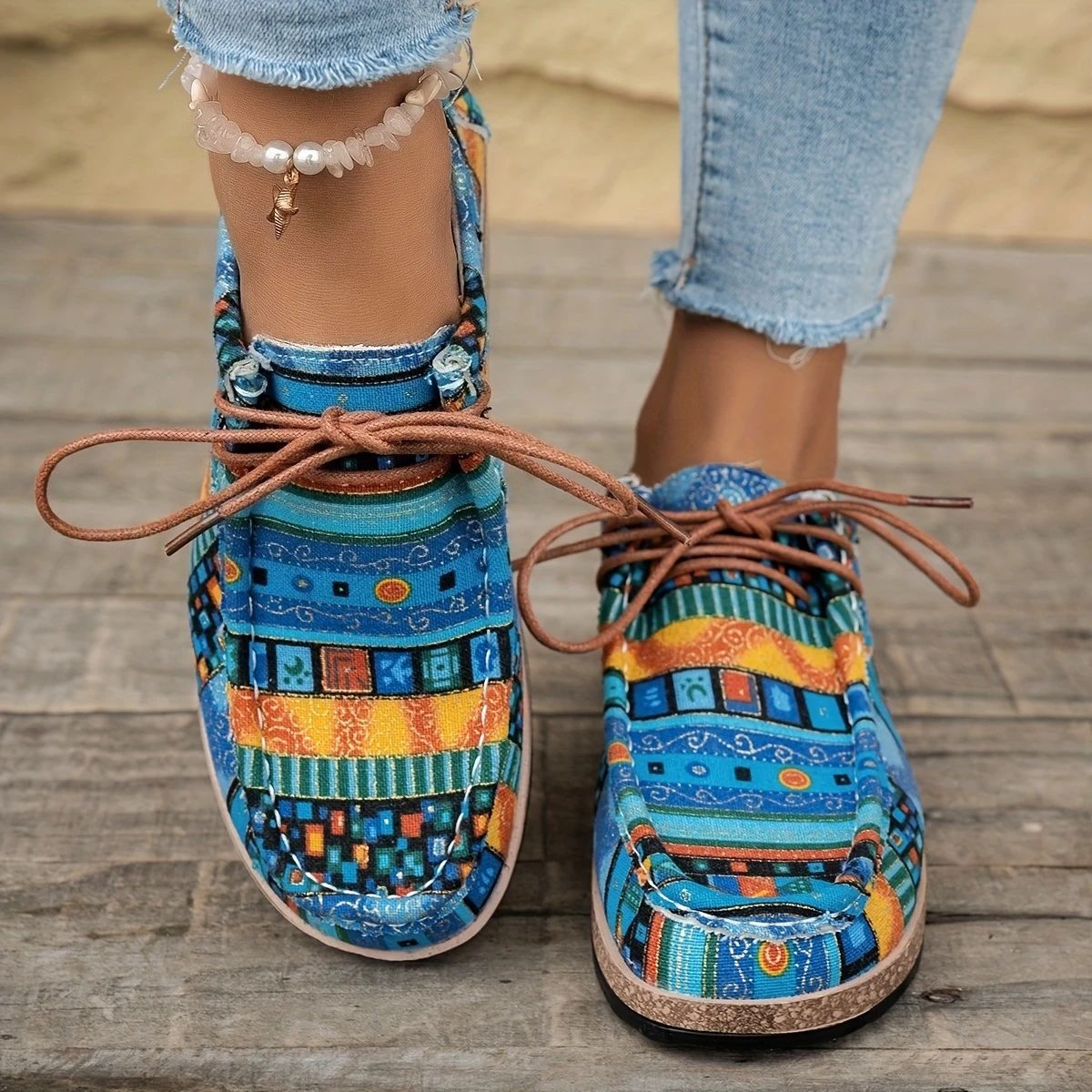 Women's casual moccasin shoes with colorful geometric pattern and brown laces, worn with skinny jeans