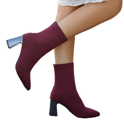 Pair of burgundy sock boots with block heels worn with a white lace skirt