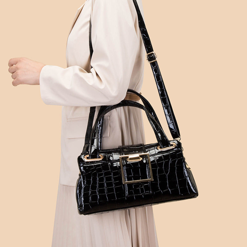 Woman wearing beige outfit carrying black croc-embossed leather handbag with gold buckle