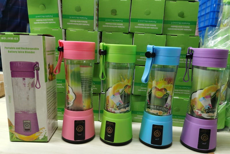 Row of pink, green, blue, and purple portable rechargeable battery juice blenders with green product boxes in background