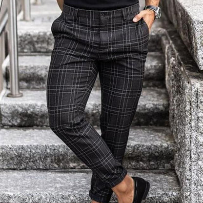 man wearing black and gray plaid slim-fit pants standing on stone stairs with hands in pockets