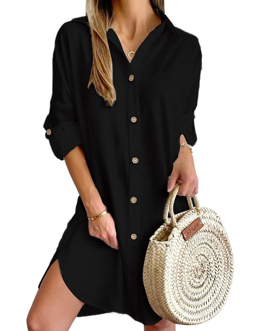 Woman wearing black button-up shirt dress with rolled sleeves holding woven round straw handbag