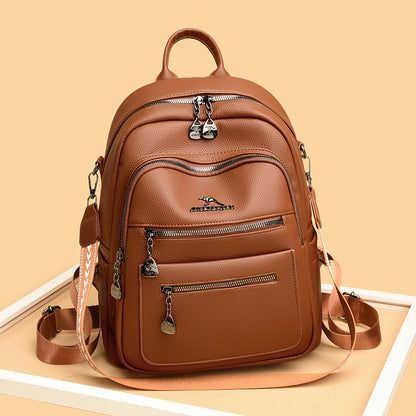 Brown leather backpack with multiple zippered compartments and adjustable straps on beige background