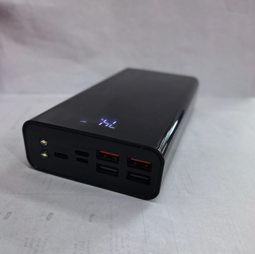 Black portable power bank with digital battery indicator and multiple USB ports on white surface